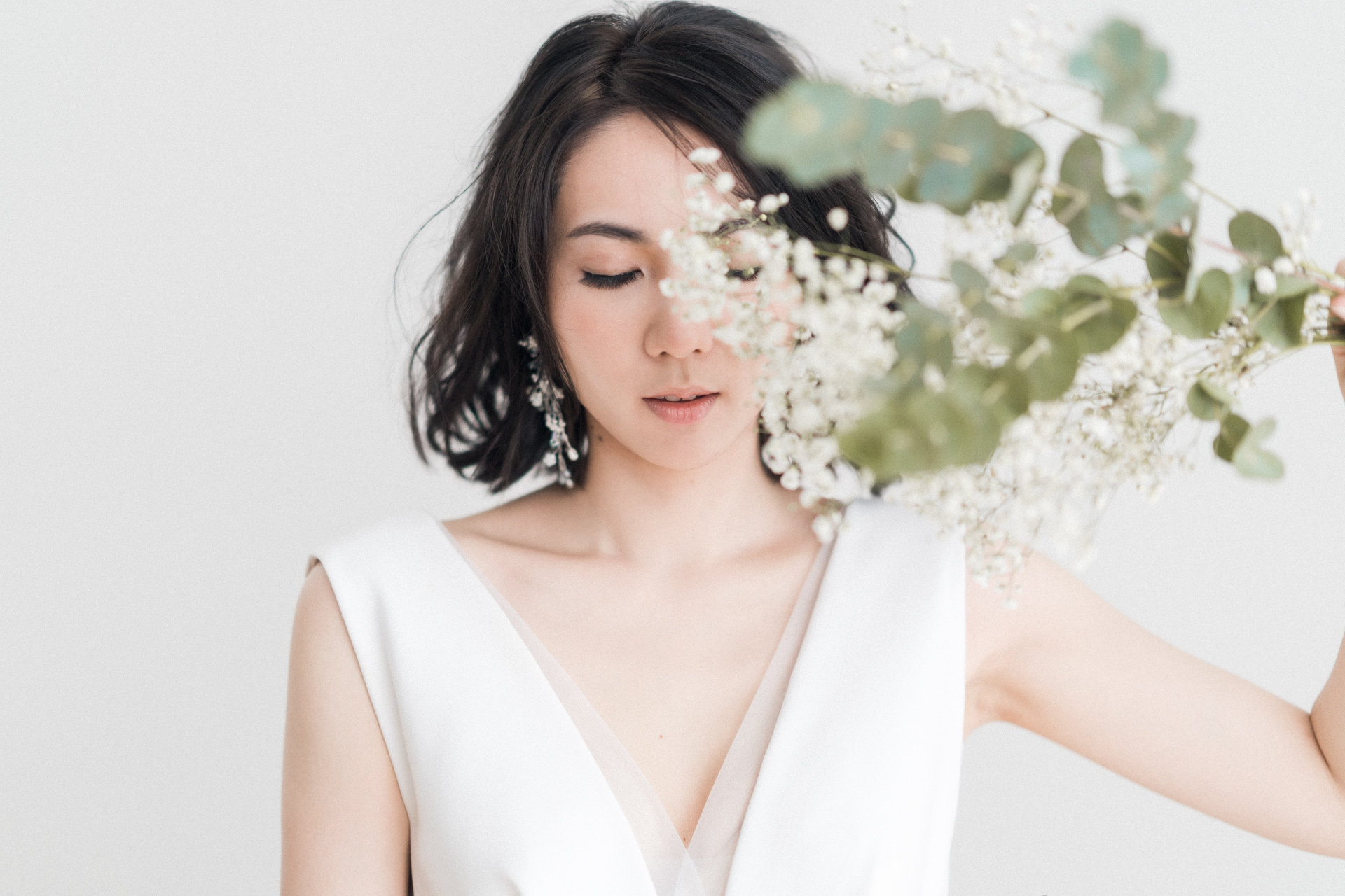 Woman in white sleeveless top with white flower.